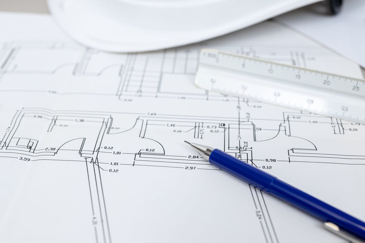 A close-up of blueprints with a blue pen resting on them