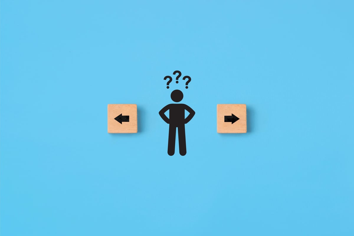 Decision making and choosing the right path. Confusion about deciding which direction to go. Stickman with question marks standing in between the wooden cubes with arrow symbols