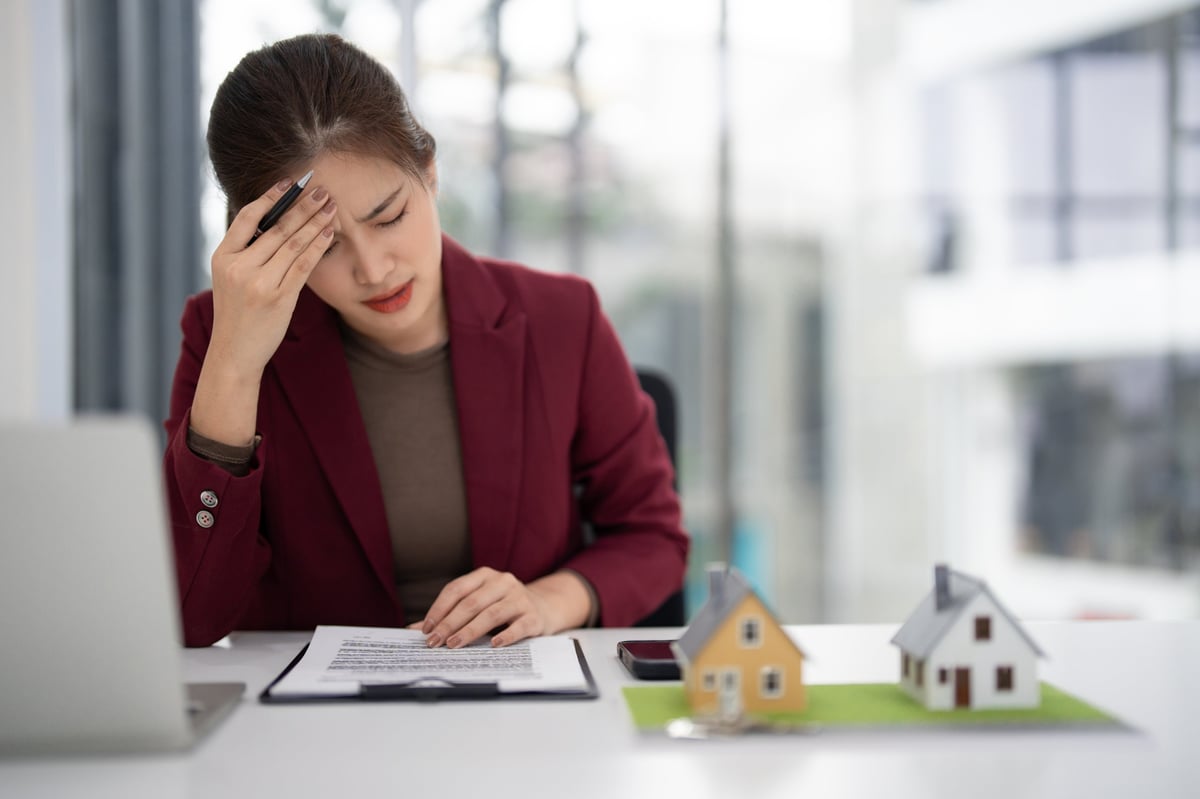 Stressed adult Asian real estate agent planning property deals