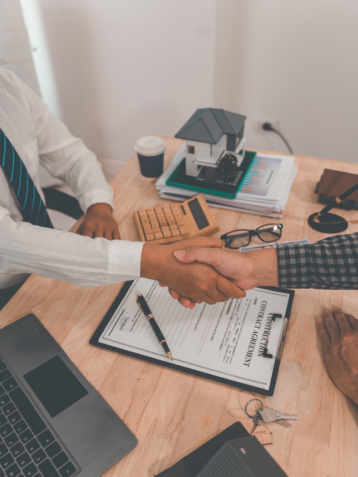 Real estate agent and client shake hands after completing a contract. After discussing home insurance, signing a contract, or completing a successful negotiation. Close-up of office environment.