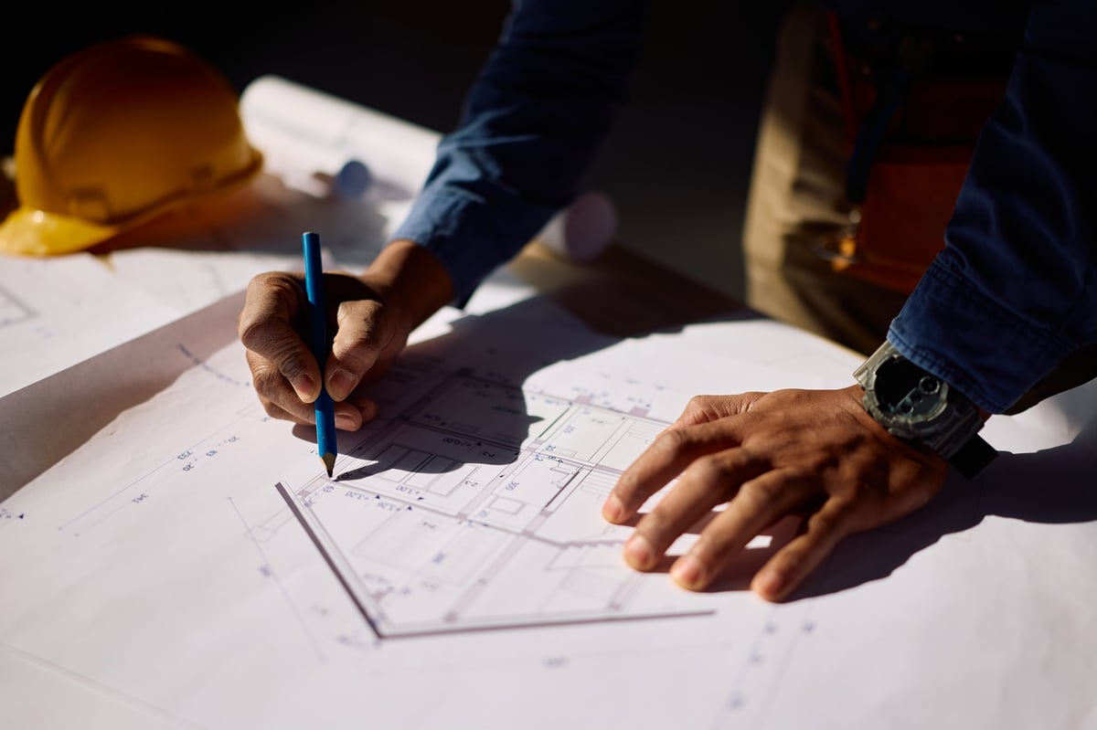 Close up of African American builder drawing housing plans on site.