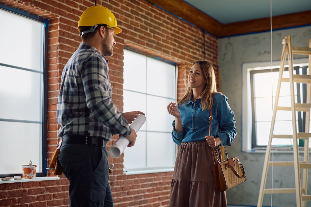 Happy woman communicating with construction worker during home remodeling project